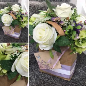 A flower arrangement of artificial roses in a gift bag